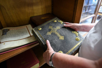 Eine Ordensfrau hält eine historische Bibelausgabe in ihren Händen in der Bibliothek im Kloster Maria Hilf der Dernbacher Schwestern am 7. August 2018 in Dernbach.