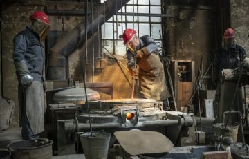 Arbeiter mit Helm und Gesichtsschutz arbeiten am Schmelzofen bei der Produktion einer Glocke, am 22. April 2022 in der Werkstatt der Glocken- und Kunstgießerei Rincker in Sinn.