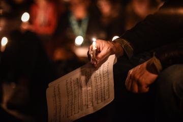Eine Hand hält eine brennende Kerze und und liegt auf einem Notenblatt am 10. Mai 2018 in Münster.