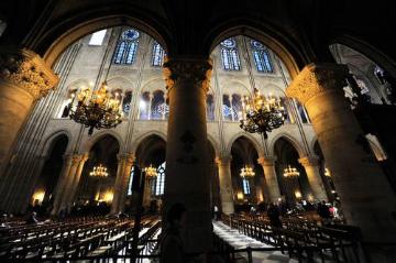 Blick aus dem Seitenschiff in das Mittelschiff der Kathedrale Notre-Dame in Paris am 6. Dezember 2013. Kronleuchter beleuchten das dunkle Langhaus. Dieses Bild ist Teil des Features "Marienwallfahrtsorte".