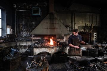 Der Schmied Georg Schmidberger arbeitet am 18. April 2018 in seiner Werkstatt in Molln (Österreich). Im Hintergrund lodert ein Feuer im Kamin.