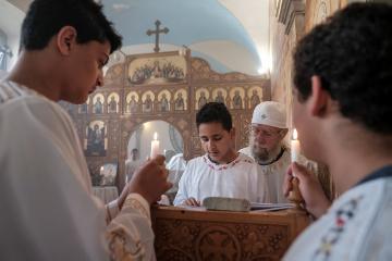 Ein junger Ministrant (m.) steht am Ambo und liest im Gottesdienst am 22. April 2018 im koptisch-orthodoxen Kloster in Höxter. Um ihn herum stehen weitere Ministranten, zwei von ihnen halten brennende Kerzen hoch.