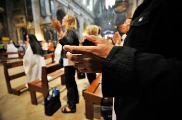 Menschen halten die Hände mit den Handflächen nach oben, während sie das Vaterunser beten, am 2. Juli 2013 in der Basilika Notre-Dame-des-Victoires in Paris.