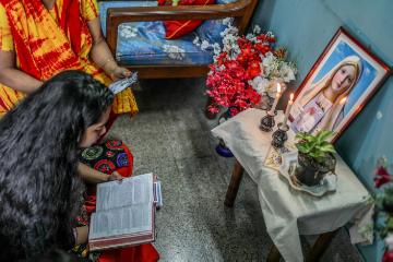 Ein Mädchen sitzt vor einem dekorierten Tisch mit Heiligenbildern und liest vor beim gemeinsamen Gebet mit der Familie im Wohnzimmer, am 7. November 2017 in Dhaka (Bangladesch).