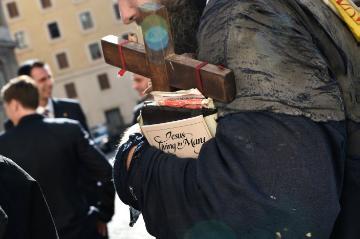 Ein Mann, Teilnehmer des katholischen "Welttag der Armen" im Vatikan, trägt zerrissene Kleidung, ein Holzkreuz und ein Buch mit der Aufschrift "Jesus. Living in Mary" am 19. November 2017.