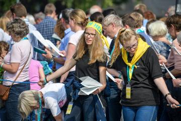 Junge Frauen haben sich Tücher umgebunden mit der Aufschrift "Ich helfe" beim Hauptgottesdienst auf dem 101. Deutschen Katholikentag am 13. Mai 2018 in Münster.