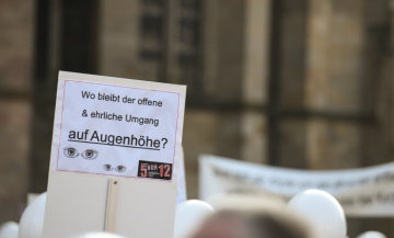 Plakat mit der Aufschrift "Wo bleibt der offene und ehrliche Umgang auf Augenhöhe?" bei der Protestaktion "5 vor 12" gegen Großpfarreien der Initiative "Kirche vor Ort" am 20. Oktober 2018 in Trier.