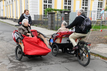 Die Ehrenamtliche Caroline Kuhl (l.) und die Seniorin Ruth Nolden in einer Rikscha am 29. Oktober 2018 in Bonn im Gespräch mit einer zweiten Fahrradgruppe.
