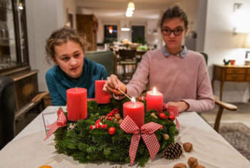 Zwei Kinder sitzen vor einem Adventskranz am 13. November 2018 in Bonn. Ein Mädchen zündet zum 2. Advent die zweite Kerze an.
