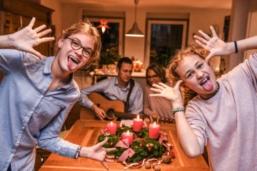 Ein Adventskranz steht auf einem Tisch am 13. November 2018 in Bonn. Zwei Mädchen schneiden Grimassen während die Eltern im Hintergrund Musik machen.