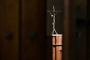 Blick durch eine leicht geöffnete Kirchentür auf ein beleuchtetes Kruzifix am 15. November 2018 in einer Kirche. (Aufnahmeort unbekannt)