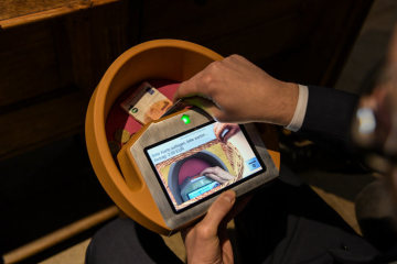 Ein Mann hält eine EC-Karte an einen digitalen Spendenkorb während der Kollekte am 17. Januar 2019 in Duisburg.
