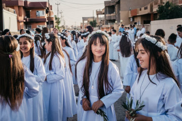 Mädchen in weißen Kleidern und mit Blumenkränzen auf dem Kopf vor ihrer Erstkommunion unter freiem Himmel in den Straßen von Karakosch (Irak) am 29. Juni 2018.