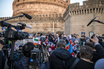 Pressevertreter mit Mikrofonen und Kameras bei der Mahnwache von Opfern von Missbrauch in der katholischen Kirche und deren Unterstützern während des Anti-Missbrauchsgipfels am 21. Februar 2019 vor der Engelsburg in Rom. Die Vertreter der Opferorganisationen halten Flaggen aus verschiedenen Ländern.