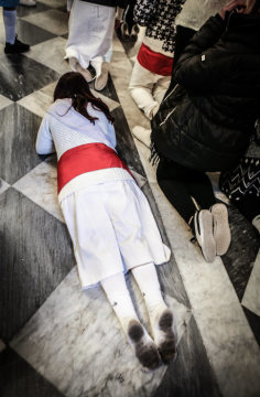 Eine in weiß gekleidete Frau liegt mit dem Gesicht nach unten zwischen knienden Menschen auf dem Boden im Santuario di Madonna dell'Arco zu Ostern am 2. April 2018 in Sant'Anastasia (Neapel).