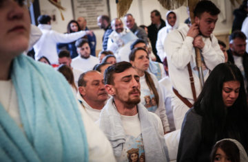 In weiß gekleidete Männer und Frauen stehen und knien andächtig auf dem Boden im Santuario di Madonna dell'Arco zu Ostern am 2. April 2018 in Sant'Anastasia (Neapel).