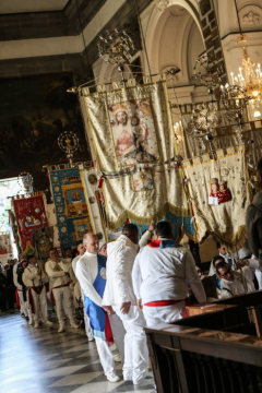 In weiß gekleidete Menschen halten mit Brokat bestickte Banner und stehen in einer Reihe im Santuario di Madonna dell'Arco zu Ostern am 2. April 2018 in Sant'Anastasia (Neapel).