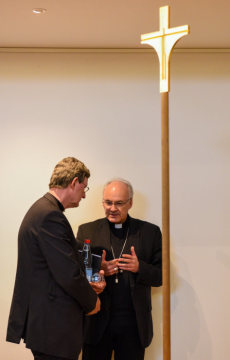 Kardinal Rainer Maria Woelki, Erzbischof von Köln, und Rudolf Voderholzer, Bischof von Regensburg, im Gespräch während der Frühjahrsvollversammlung der Deutschen Bischofskonferenz (DBK) am 11. März 2019 in Lingen. Sie stehen neben einem Kreuz.