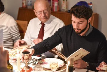 Eine Familie sitzt während der Feier des Sederabends zum Pessachfest am 10. April 2017 am gedeckten Tisch in Bonn. Ein Mann liest aus der Haggada, dem Buch mit den Handlungsanweisungen für den Seder.