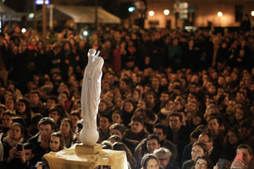 Menschen beten vor der Statue der Muttergottes von Notre-Dame vor der Kathedrale Notre-Dame in Paris am 16. April 2019.