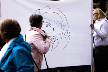 Frauen mit einem Plakat, das eine Frau mit zugeklebtem Mund zeigt, bei einer Mahnwache der Initiative "Maria 2.0" am 12. Mai 2019 vor dem Dom in Münster.