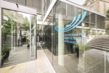Ein Logo der Hochschule für Jüdische Studien Heidelberg (HfjS) befindet sich an der Glasfassade neben dem Eingang mit Sicherheitstür am 27. Mai 2019.
