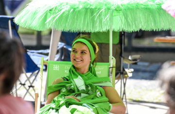 Bei der Eröffnung des Deutschen Evangelischen Kirchentags (DEKT) am 19. Juni 2019 in Dortmund sitzt eine junge Frau, bekleidet mit grünen Kirchentagsschals, in einem grünen Regiestuhl unter einem grünen Sonnenschirm.