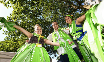 Bei der Eröffnung des Deutschen Evangelischen Kirchentags (DEKT) am 19. Juni 2019 in Dortmund lachen Jugendliche in die Kamera mit erhobenen Armen, bekleidet mit grünen Kirchentagsschals.