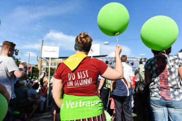 Eine Helferin mit rotem T-Shirt und gelbem Halstuch hält einen grünen Luftballon bei der Eröffnung des Deutschen Evangelischen Kirchentags (DEKT) am 19. Juni 2019 in Dortmund. Das T-Shirt trägt die Aufschrift auf dem Rücken "Ich bin ein Gewinn".