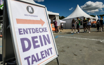 Ein Schild mit der Aufschrift "Der Pfarrberuf - Entdecke dein Talent" steht am 21. Juni 2019 auf dem Deutschen Evangelischen Kirchentag (DEKT) in Dortmund. Menschen stehen im Hintergrund.