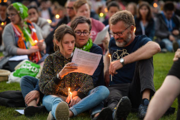 Eine Familie sitzt mit brennenden Kerzen zwischen anderen Menschen auf einer Wiese, bei der "Nacht der Lichter", am 21. Juni 2019 auf dem Deutschen Evangelischen Kirchentag (DEKT) in Dortmund.