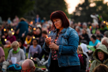 Eine Frau steht mit einer brennenden Kerze zwischen sitzenden Menschen bei der "Nacht der Lichter", am 21. Juni 2019 auf dem Deutschen Evangelischen Kirchentag (DEKT) in Dortmund.