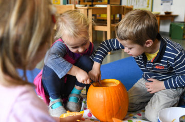 Ein Mädchen und ein Junge sitzen am 12. Oktober 2018 in einem Kindergarten in Bonn auf dem Boden und höhlen mit Löffeln einen Kürbis aus.