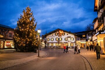 Passanten gehen auf einem Platz an einem beleuchteten Christbaum vorbei im Zentrum von Oberammergau am 7. Dezember 2019 in Oberammergau.