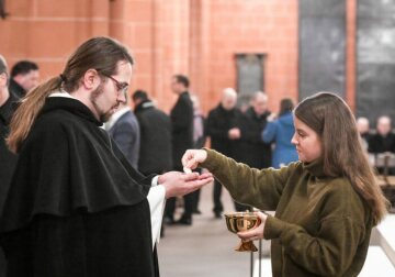 Eine junge Frau spendet die Kommunion an einen Geistlichen beim Gottesdienst während der Synodalversammlung am 31. Januar 2020 im Frankfurter Dom Sankt Bartholomäus.