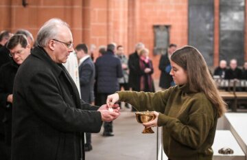 Eine junge Frau spendet die Kommunion an Rudolf Voderholzer, Bischof von Regensburg, beim Gottesdienst während der Synodalversammlung am 31. Januar 2020 im Frankfurter Dom Sankt Bartholomäus.