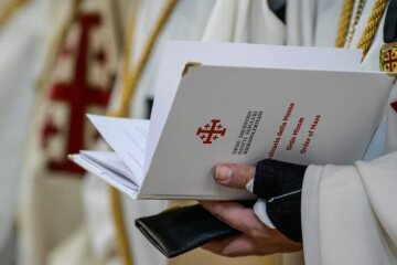 Hände halten eine Messordnung mit dem Wappen des Ritterordens vom Heiligen Grab zu Jerusalem am 1. Februar 2020 in Rom.
