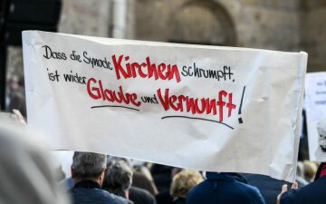 Plakat mit der Aufschrift "Dass die Synode Kirchen schrumpft, ist wider Glaube und Vernunft" bei der Protestaktion "5 vor 12" gegen Großpfarreien der Initiative "Kirche vor Ort" am 20. Oktober 2018 in Trier.