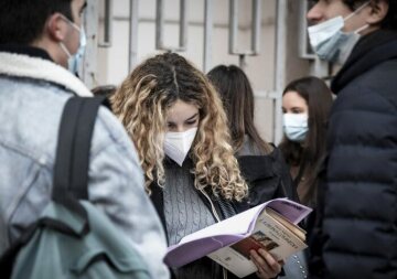 Eine Schülerin mit Maske liest in einem Schulbuch vor dem Schulgebäude, nach der Wiedereröffnung des Gymnasiums Giulio Cesare am 18. Januar 2021 in Rom.