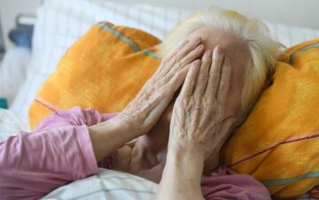 Eine Frau liegt im Pflegebett und hält ihre Hände zum Gebet vor ihr Gesicht auf der Palliativstation in der Universitätsklinik Bonn am 12. März 2021.