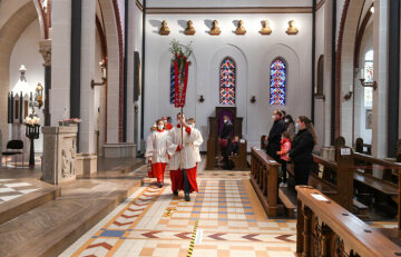 Messdiener gehen mit einem Kruzifix in einer Prozession an den Gottesdienstteilnehmern vorbei während des Gottesdienstes an Palmsonntag in der Kirche Sankt Sebastian am 28. März 2021 in Bonn.