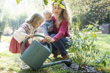 Ein Mutter mit zwei Kindern wässert mit einer Gießkanne einen Busch in einem Garten am 20. Oktober 2018. (Aufnahmeort unbekannt)