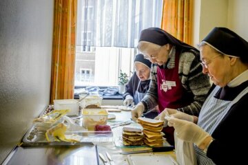 Ordensfrauen des Schervier-Ordens schmieren Butterbrote und verpacken sie in Papiertüten am 25. März 2020 für ihre Lebensmittelausgabe für Obdachlose und andere Bedürftige in Aachen. Sie tragen Einmalhandschuhe.