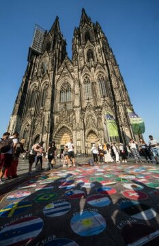 Touristen stehen am 2. August 2018 auf der Domplatte vor dem Kölner Dom um eine Kreidezeichnung von unterschiedlichen Nationalflaggen.