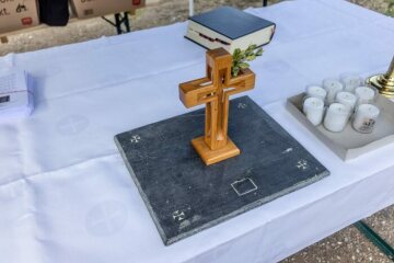 Auf dem provisorischen Altar steht ein Kreuz und die Platte mit der Reliquie beim Entwidmungsgottesdienst im Freien auf dem Außengelände der Kirche Sankt Andreas am 16. September 2022 in Ahrbrück.