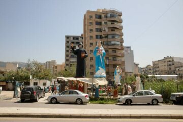 Geschäft mit Heiligenfiguren an einer Straße in Antelias (Libanon) am 6. April 2021. Das Gelände wird überragt von einer großen Statue des Heiligen Scharbel Machluf (l.) und der Jungfrau Maria mit dem Christuskind.
