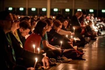 Teilnehmer sitzen auf dem Boden und halten brennende Kerzen während des Gottesdienstes "Nacht der Lichter" auf dem 101. Katholikentag in Münster am 10. Mai 2018.