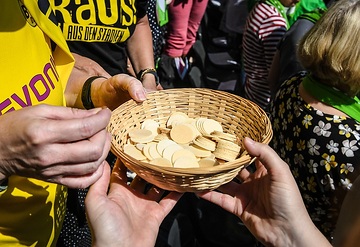 Hände halten einen Korb mit Oblaten bei der Abendmahlsfeier am 23. Juni 2019 im Schlussgottesdienst des Deutschen Evangelischen Kirchentags (DEKT) in Dortmund.