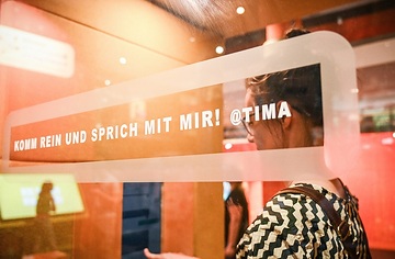 Eine Besucherin spricht in einer Telefonzelle mit einem Sprachassistenten in der Ausstellung "Mission KI" im Deutschen Museum Bonn am 1. August 2023 in Bonn.