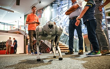 Ein Mitarbeiter, genannt "Museotainer", führt einen laufenden kleinen Roboter vor in der Ausstellung "Mission KI" im Deutschen Museum Bonn am 1. August 2023 in Bonn.